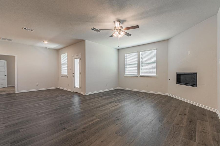 Unfurnished living room featuring ceiling fan and dark hardwood / wood-style flooring