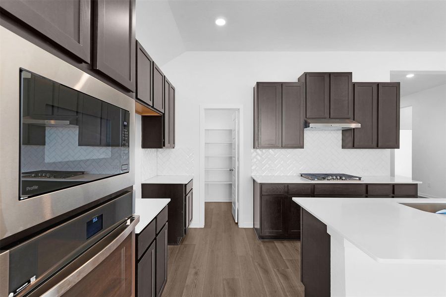 Kitchen featuring backsplash, stainless steel appliances, light wood-style flooring, recessed lighting, and light stone counters