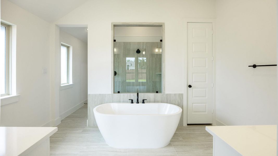 Full bathroom featuring a soaking tub, vanity, a stall shower, and baseboards