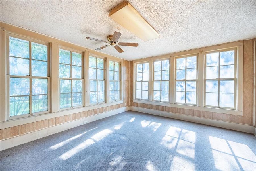 Unfurnished sunroom with ceiling fan and a wealth of natural light