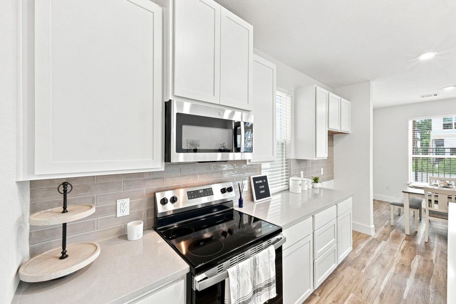 Modern kitchen featuring abundant cabinetry, quartz countertops, tile backsplash, and stainless-steel appliances, with plenty of counter space for everyday cooking and entertaining. Modern kitchen featuring abundant cabinetry, quartz countertops, tile backsplash, and stainless-steel appliances, with plenty of counter space for everyday cooking and entertaining.