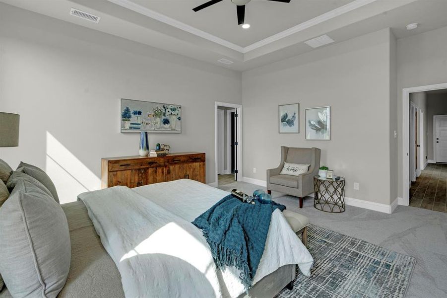 Carpeted bedroom featuring a tray ceiling, ornamental molding, and ceiling fan