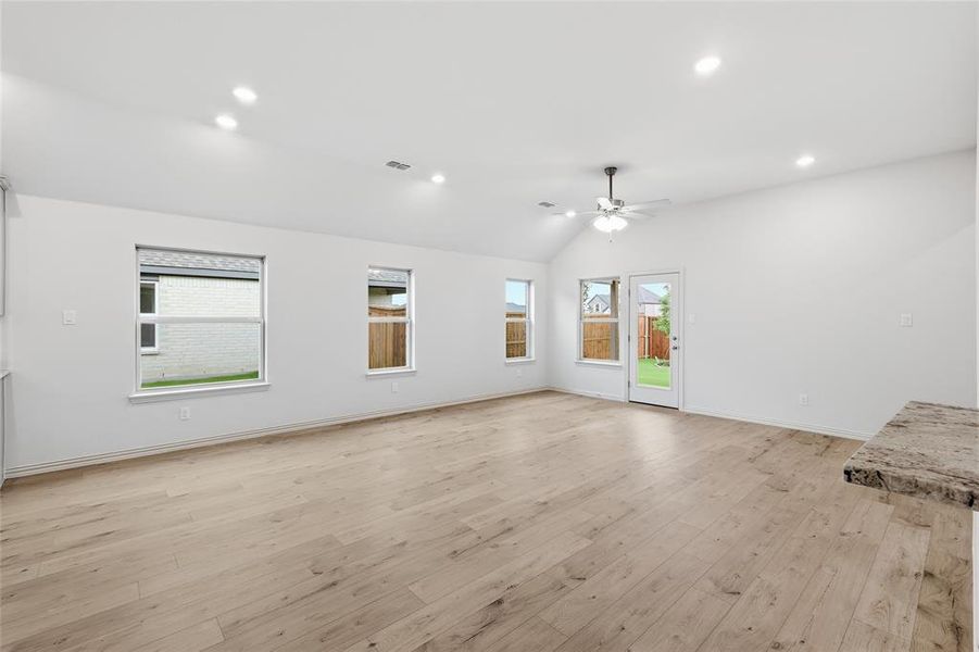 Spacious room featuring wood-finish flooring, multiple windows, a vaulted ceiling, recessed lighting, and a ceiling fan Spacious room featuring wood-finish flooring, multiple windows, a vaulted ceiling, recessed lighting, and a ceiling fan