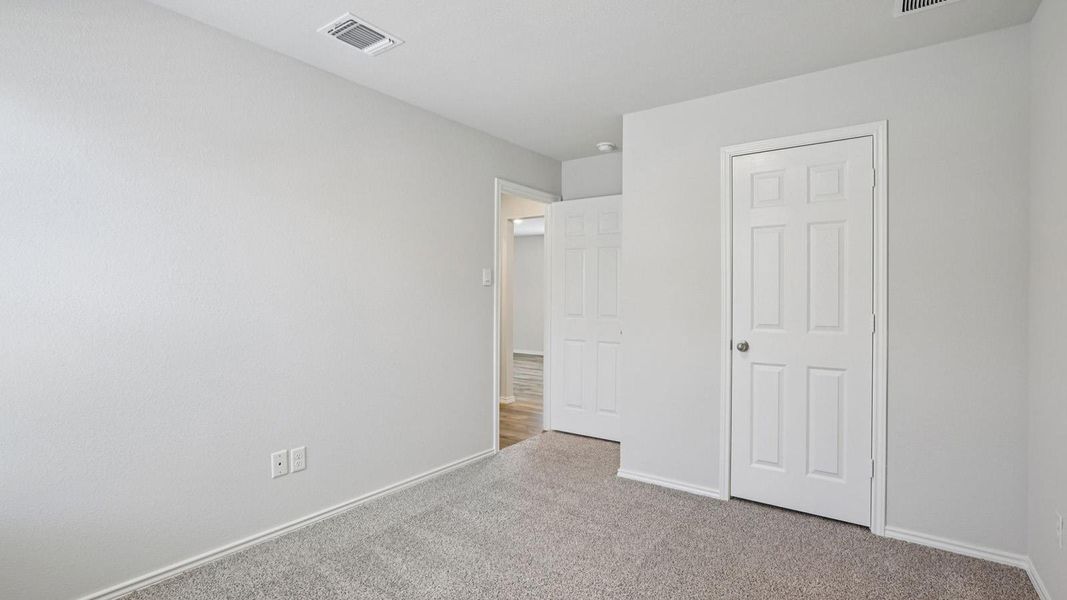 Unfurnished bedroom with light colored carpet and baseboards