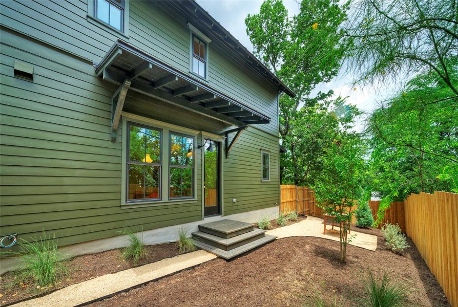 A striking exterior featuring a covered entryway and a freshly mulched private yard.