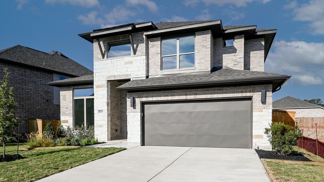 Modern home with stone siding, concrete driveway, and a shingled roof Modern home with stone siding, concrete driveway, and a shingled roof