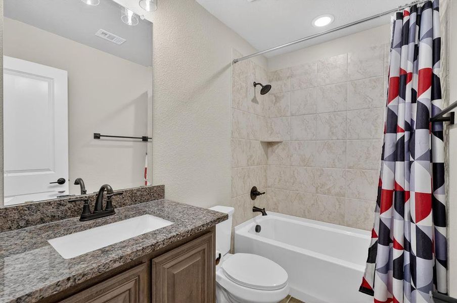 Full bathroom featuring a granite-style countertop, undermount sink, and dark bronze-finish fixtures Full bathroom featuring a granite-style countertop, undermount sink, and dark bronze-finish fixtures