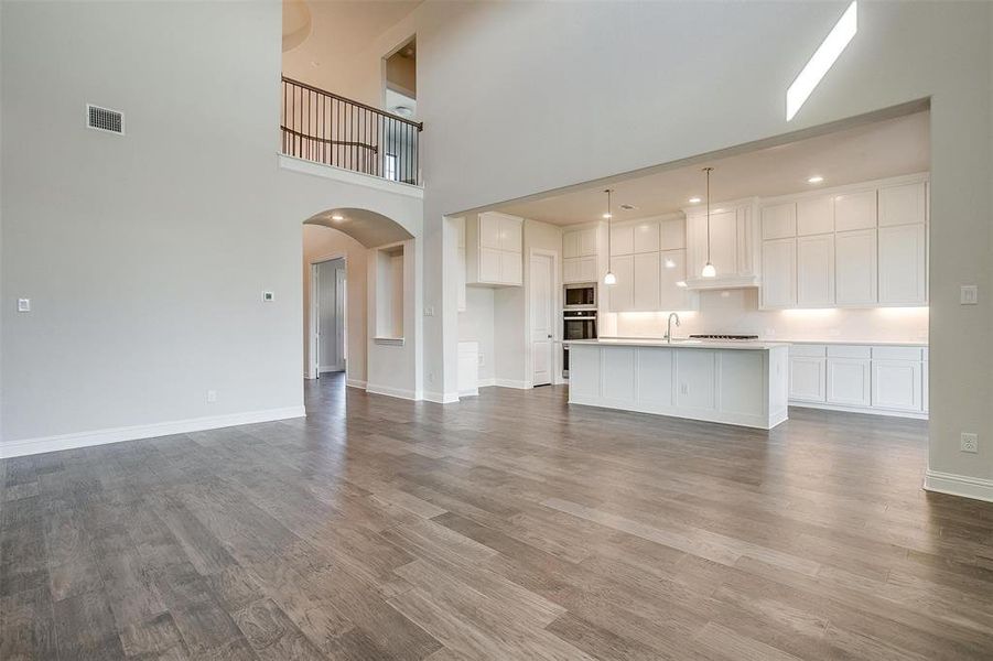 Unfurnished living room with light wood-type flooring, a towering ceiling, and sink