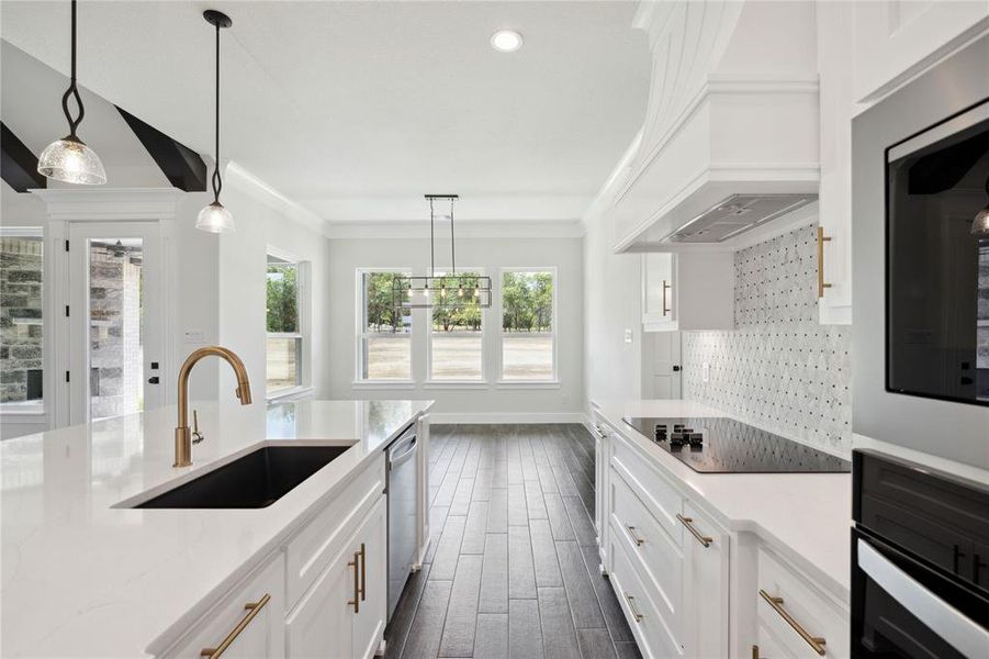 Kitchen with white cabinetry, backsplash, premium range hood, black appliances, and sink