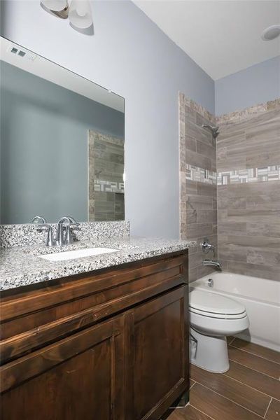 Full bathroom with tiled shower / bath, vanity, and toilet