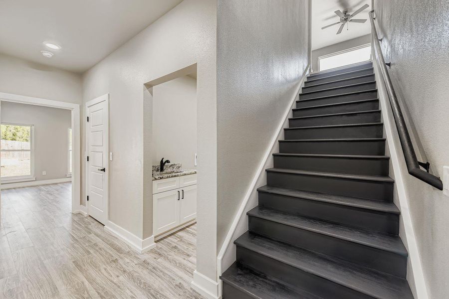 Stairs featuring plenty of natural light, wood finished floors, and a ceiling fan