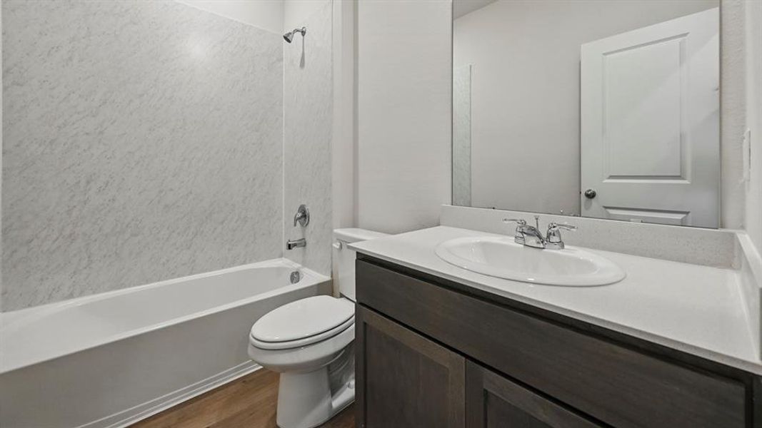 Bathroom with dark wood-type flooring,  shower combination, and vanity