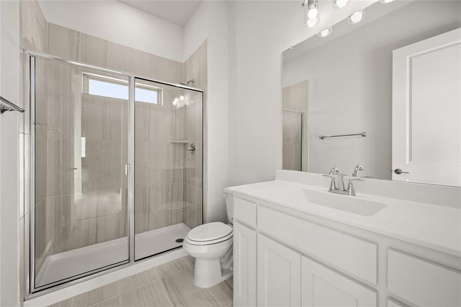 Secondary Bathroom featuring tile patterned floors, vanity, toilet, and a shower with shower door