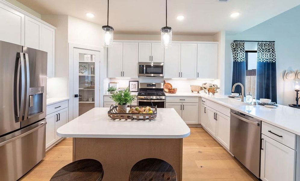 What a wonderful kitchen to gather in! This spacious open concept kitchen features a large center island with seating, ample counter space, and a bright layout that flows beautifully into the dining and family areas, complemented by stunning wood looking tile flooring throughout the main living areas, ideal for everyday living and entertaining. What a place to gather and make this home yours. **Photos are representative only and may vary as built.**