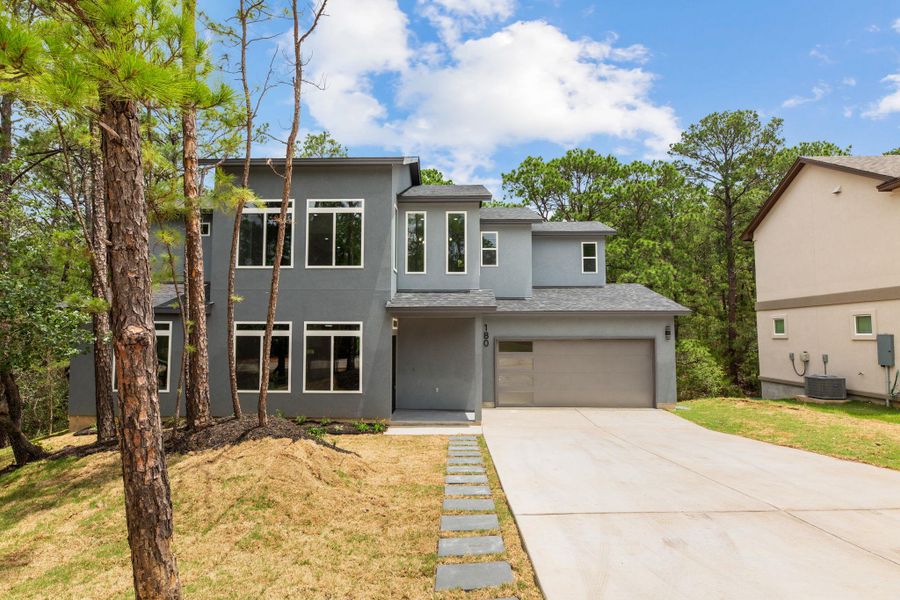 Modern architecture and tall windows define this inviting residence nestled among mature trees.