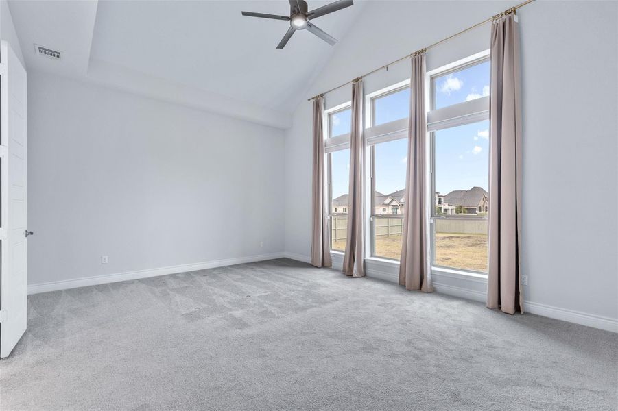 Unfurnished room featuring high vaulted ceiling, light colored carpet, a ceiling fan, and a residential view
