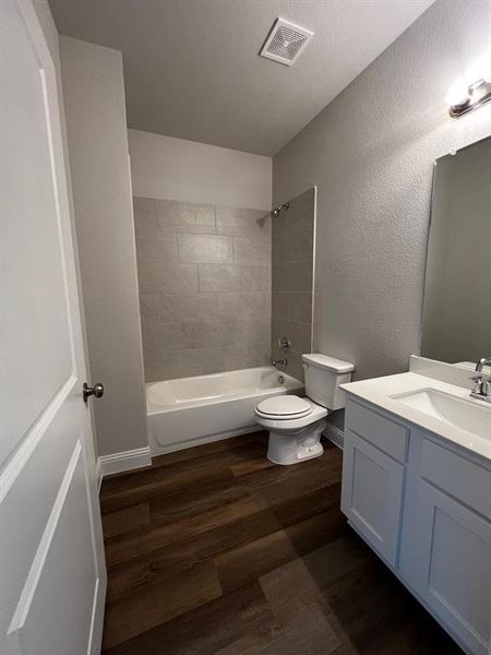 Full bathroom featuring vanity, toilet, hardwood / wood-style floors, and tiled shower / bath