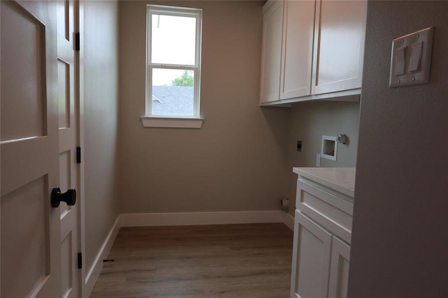 Washroom with washer hookup, wood-type flooring, hookup for an electric dryer, and cabinets