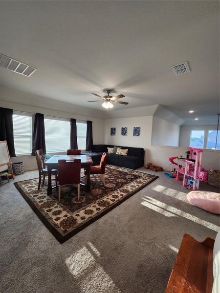 An open-concept living area features ample natural illumination and a functional ceiling fan for comfort.