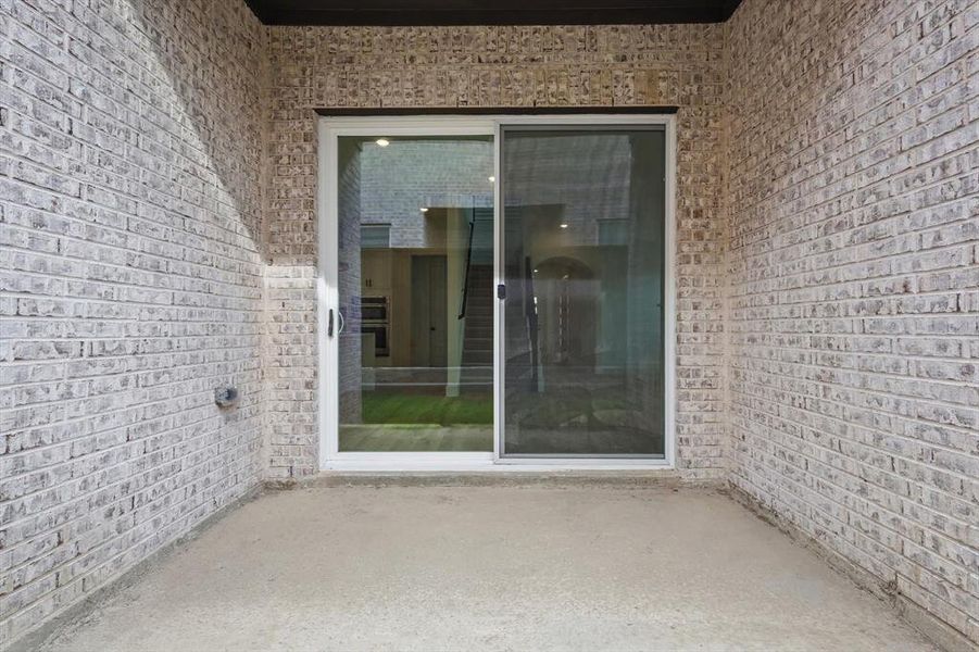 Doorway to property featuring brick siding and a patio