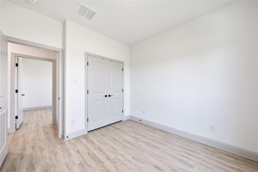 Unfurnished bedroom with light wood-type flooring and a closet
