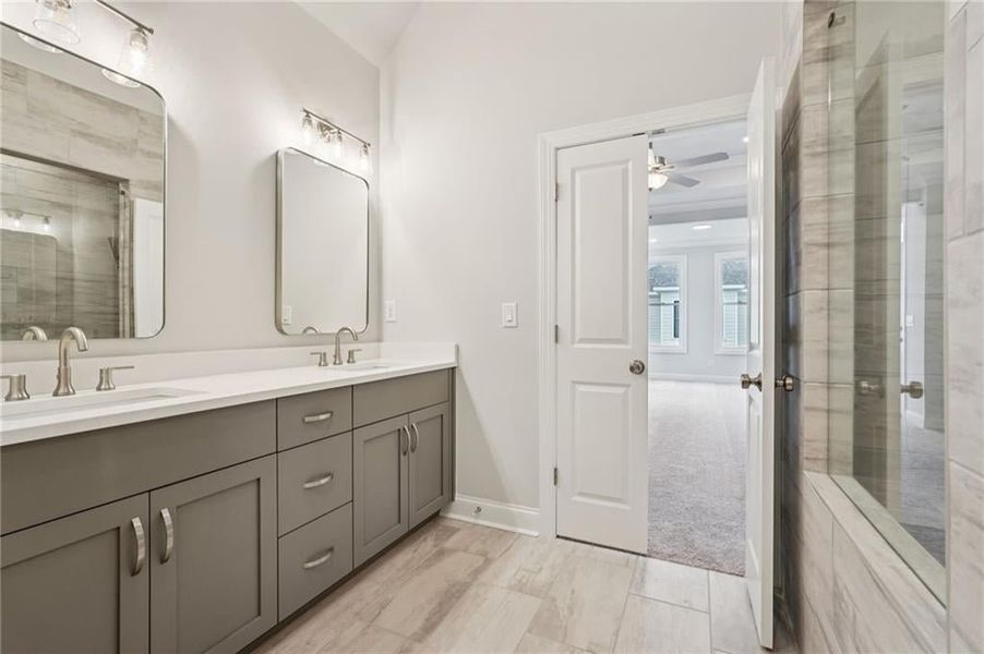 Full bathroom featuring a shower stall, double vanity, and ceiling fan