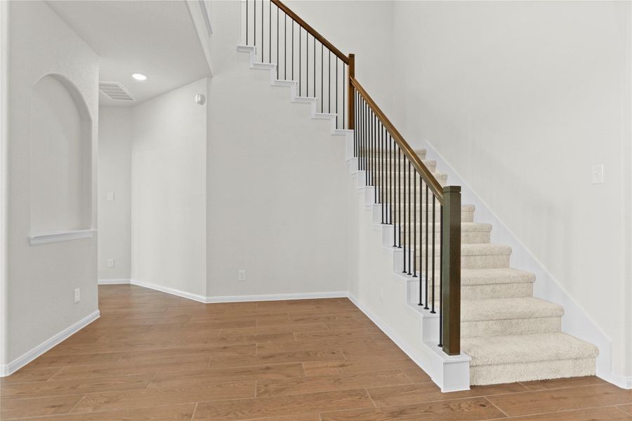 Elegant view of the staircase featuring beautiful railing details that lead to the second floor living spaces. The staircase sits perfectly within the open concept design, while the wood looking tile flooring continues to add style and durability throughout the first floor.