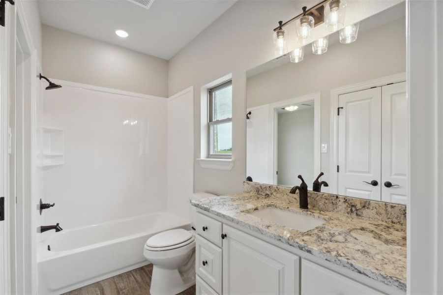 Full bathroom with vanity, toilet, washtub / shower combination, and hardwood / wood-style flooring