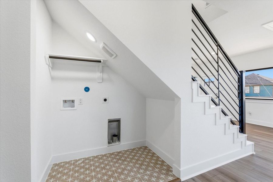 Tucked beneath the staircase is a designated laundry nook featuring decorative tile flooring and a hanging shelf. An electric dryer connection is already in place, making this space both functional and thoughtfully designed. Tucked beneath the staircase is a designated laundry nook featuring decorative tile flooring and a hanging shelf. An electric dryer connection is already in place, making this space both functional and thoughtfully designed.