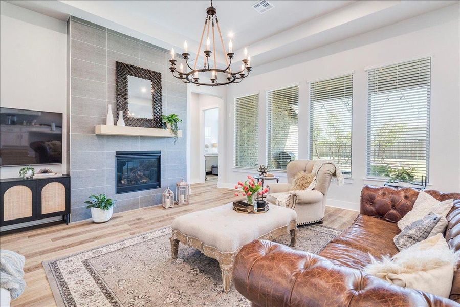 Living area with wood finished floors, suspended lighting, and a tiled fireplace Living area with wood finished floors, suspended lighting, and a tiled fireplace