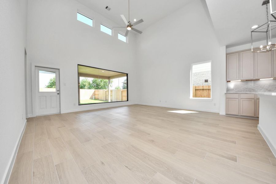 Relax and unwind in this inviting family room, illuminated by abundant natural light streaming in through tall windows, complemented by high ceilings and stunning flooring. Stay comfortable year-round with the gentle breeze from the ceiling fan, creating the perfect atmosphere for family gatherings. Sample photo of completed home with similar floor plan. Actual colors and selections may vary.