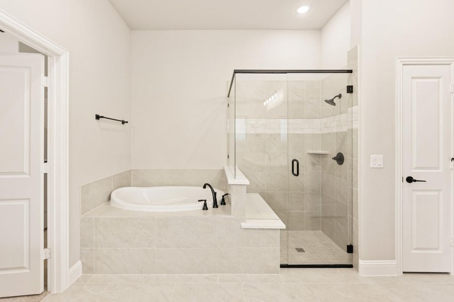 Master bathroom with soaking tub, glass walk-in shower, tile surround, and black fixtures Master bathroom with soaking tub, glass walk-in shower, tile surround, and black fixtures