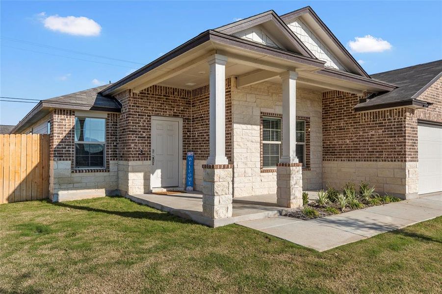 Doorway to property featuring covered porch, brick siding, stone siding, a garage, and a shingled roof