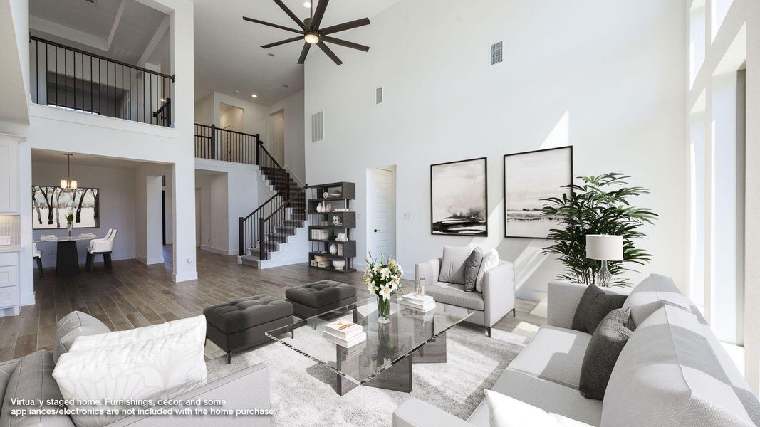 Living room with wood finished floors, a towering ceiling, ceiling fan, and stairs