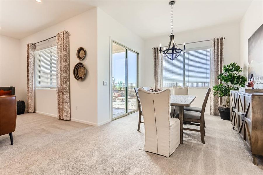 Dining space with light colored carpet and a chandelier