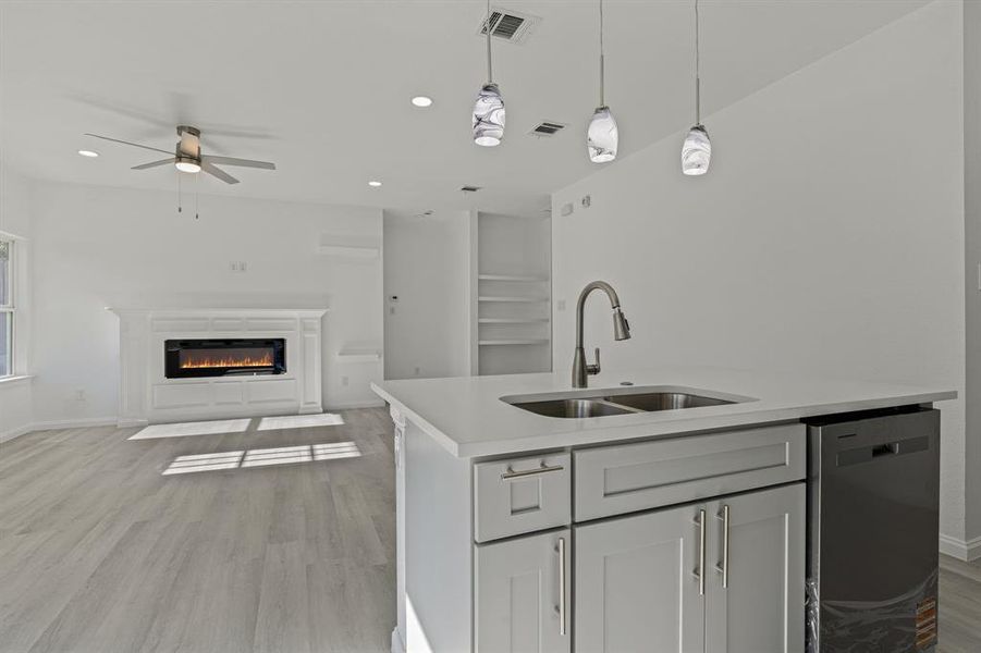 Kitchen with open floor plan, pendant lighting, stainless steel dishwasher, a fireplace with flush hearth, and recessed lighting