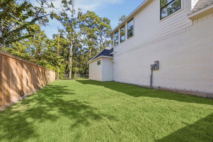 Side yard with fenced privacy, generous green space, and exterior access door.