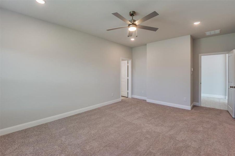 Spacious room with plush carpeting, recessed lighting, and a contemporary ceiling fan