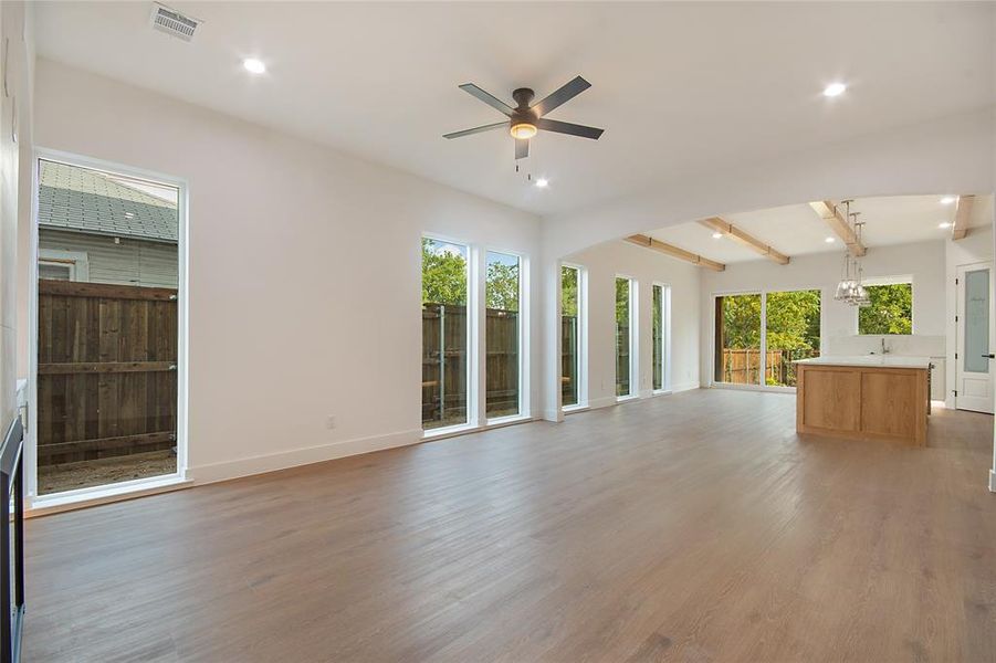 Unfurnished living room featuring beam ceiling, light wood-style floors, plenty of natural light, recessed lighting, and a ceiling fan