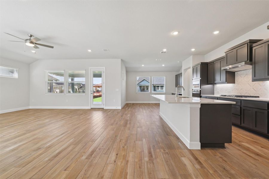Kitchen featuring a kitchen island with sink, open floor plan, light countertops, and recessed lighting