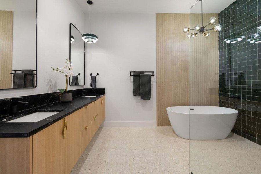 Full bath with double vanity, a freestanding tub, a chandelier, walk in shower, and tile walls