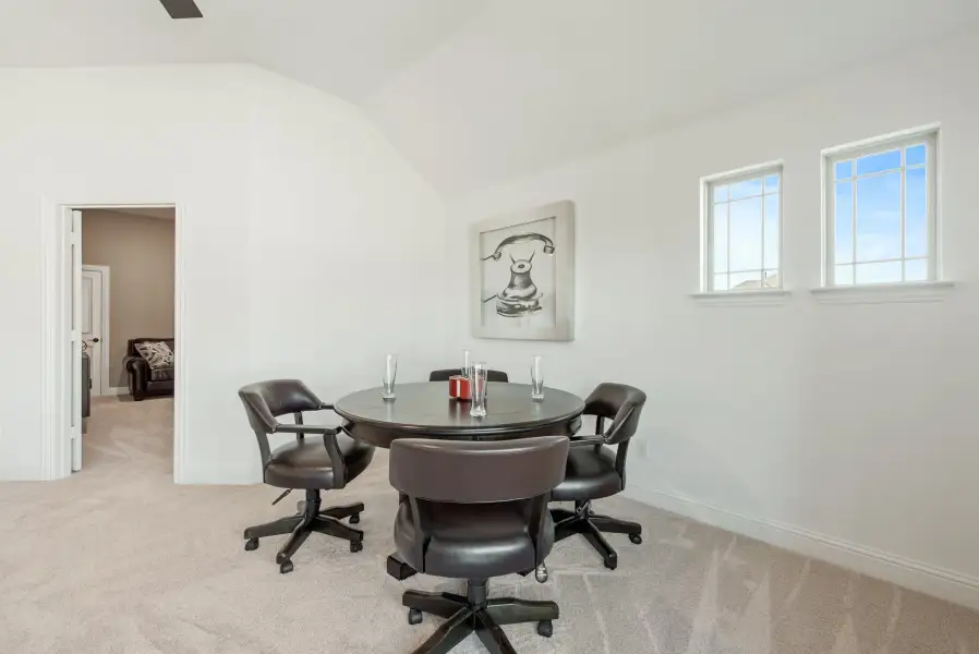 Bonus room with round table, four rolling chairs, vaulted ceiling, and carpet flooring