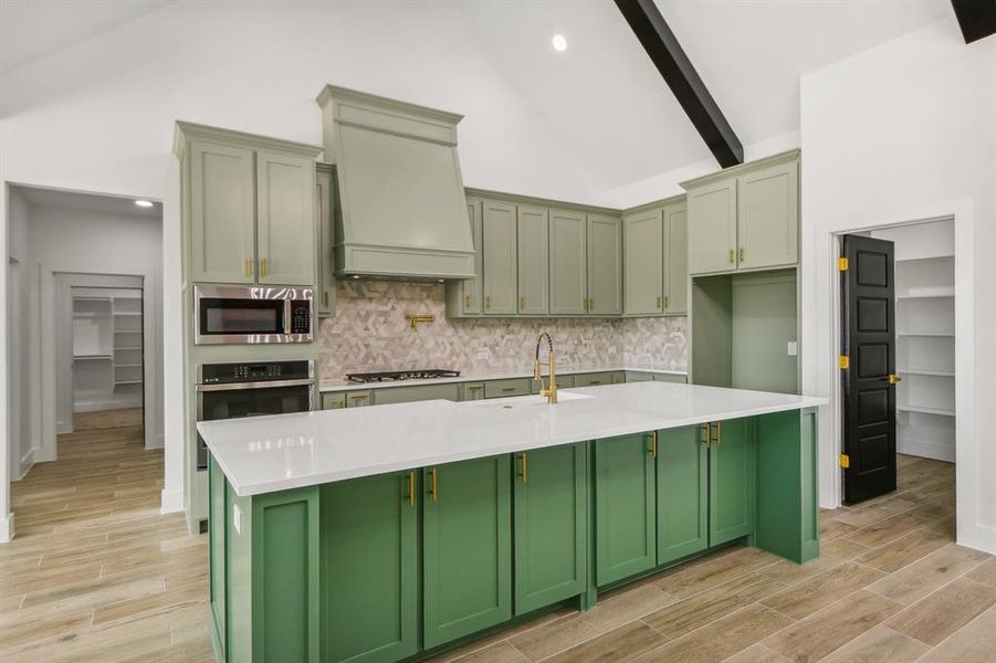 Kitchen featuring green cabinetry, wood finish floors, decorative backsplash, light stone counters, and high vaulted ceiling Kitchen featuring green cabinetry, wood finish floors, decorative backsplash, light stone counters, and high vaulted ceiling