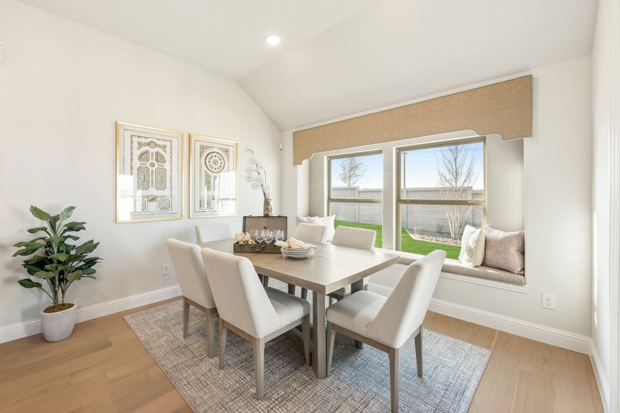 Dining room with six-chair table, vaulted ceiling, and built-in window seat overlooking backyard
