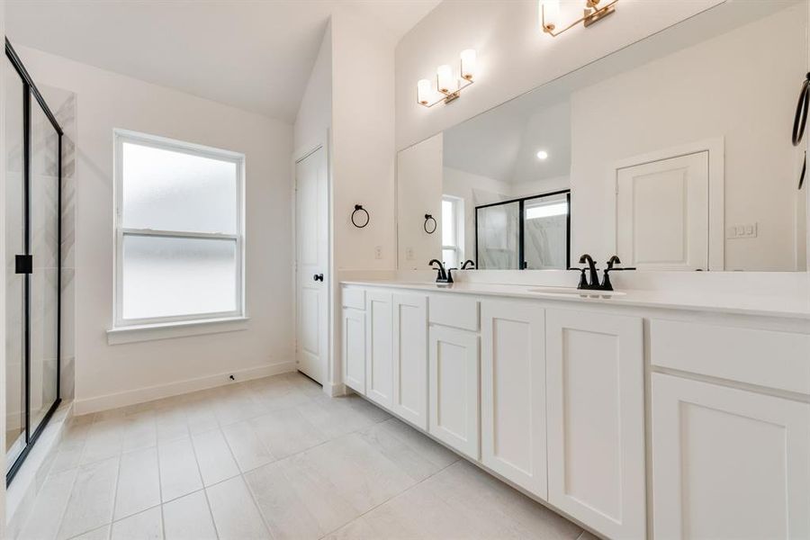 Full bathroom with double vanity, a marble finish shower, light tile patterned flooring, and lofted ceiling Full bathroom with double vanity, a marble finish shower, light tile patterned flooring, and lofted ceiling