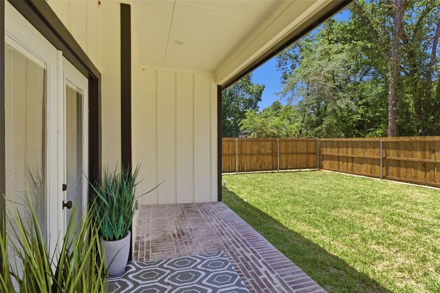 Covered patio featuring brick-finish flooring, white board and batten siding, and recessed lighting