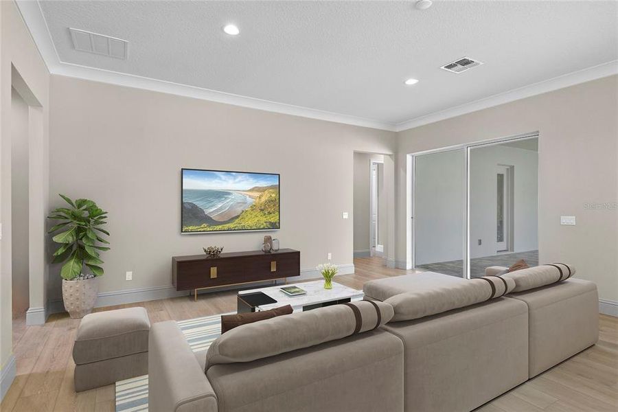 Seamlessly flowing from the kitchen and dining area, this spacious living room is a central gathering place, showcasing the home's open and thoughtful design. The room is elevated by beautiful flooring, elegant crown molding, and recessed lighting that creates a bright and inviting atmosphere. Sliding glass doors connect this space to the spacious backyard patio.