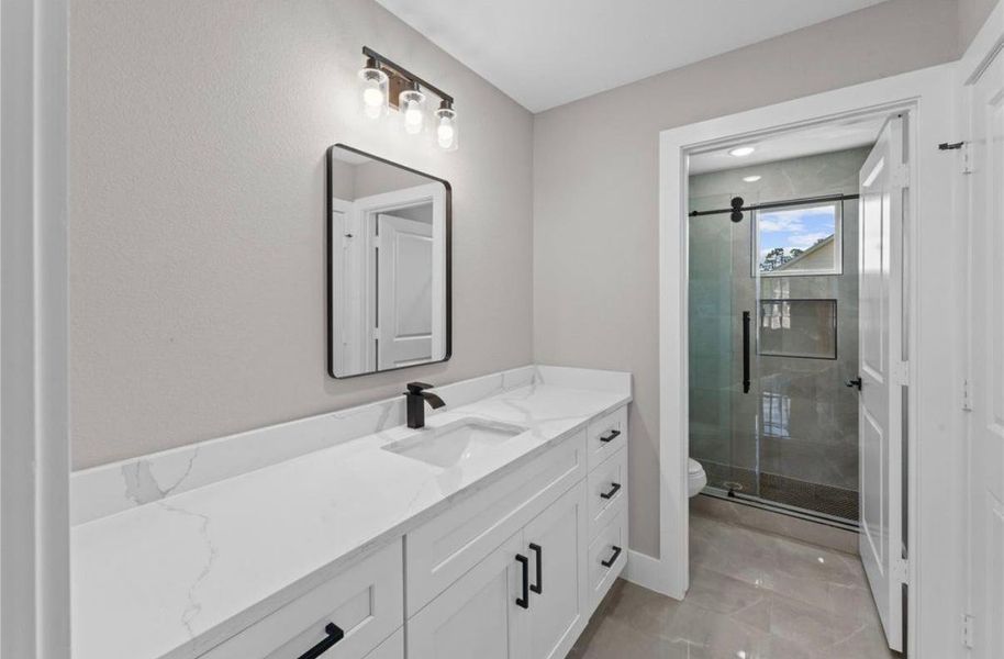 Modern and stylish second bathroom featuring a sleek vanity, elegant lighting, and a spacious glass-enclosed shower.