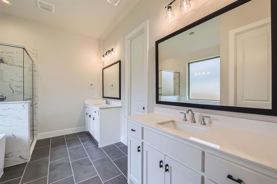 Bathroom featuring a marble finish shower, two vanities, and tile patterned flooring Bathroom featuring a marble finish shower, two vanities, and tile patterned flooring