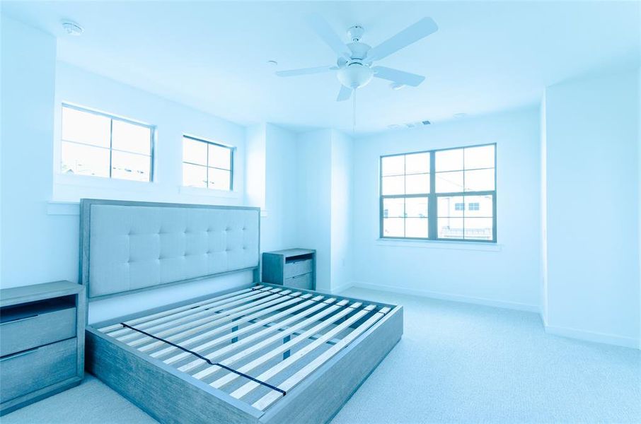 Bedroom with multiple windows, light colored carpet, and ceiling fan